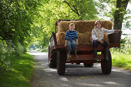 两个男孩在拖拉机拖车上人力车树
