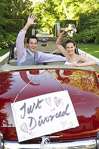 快乐的夫妇在一辆敞篷车挥舞着刚刚离婚的标志上