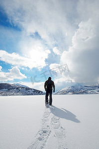 远走高飞摄影照片_人在纯净的雪地上穿着雪鞋