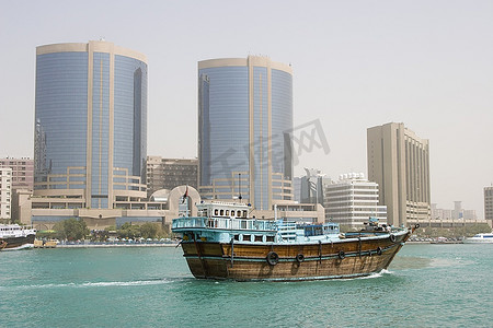 阿联酋迪拜，劳力士铁塔前，一艘古老的木制帆船沿着迪拜小溪航行。