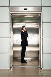电梯里摄影照片_商务人士在电梯里使用手机