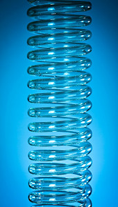 深蓝色蓝色摄影照片_深蓝色背景的蒸馏器线圈玻璃
