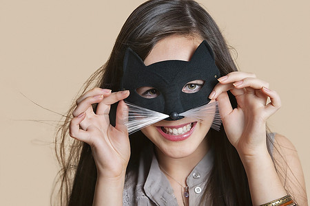 一名年轻女子在彩色背景下通过眼罩模仿猫的肖像
