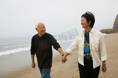 一对情侣牵着手在海滩上散步
