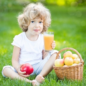 快乐的孩子在春天公园喝苹果汁