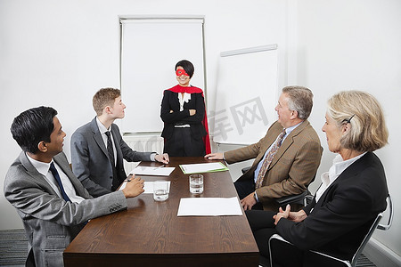 越过摄影照片_作为超级英雄的商业领袖在同事面前在会议在会议室