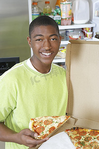 tshirt摄影照片_年轻人吃比萨饼在家里