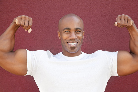 一位快乐的非裔美国人在彩色背景上展示肌肉的肖像