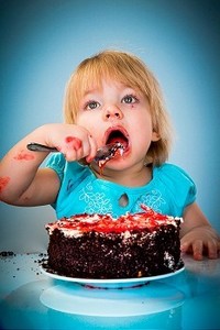 小女婴吃蛋糕在一个蓝色背景
