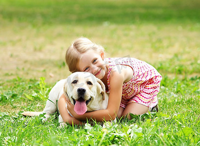 一个金发小女孩带着她的宠物狗在公园外面