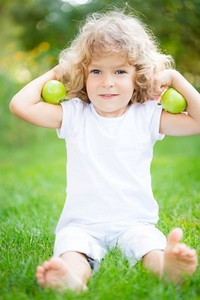 春天公园里，快乐的孩子在绿色的草地上玩苹果