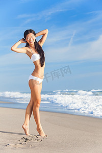 亚洲比基尼摄影照片_一个美丽的中国亚洲年轻女子或女孩穿着白色比基尼在空无一人的热带海滩与蓝天