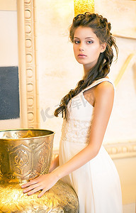 金色婚礼装饰摄影照片_奢华的波什·布鲁内特穿着白色连衣裙。东方古董金色装饰