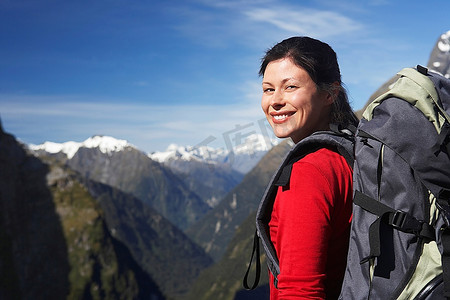 背着双肩包的女徒步旅行者在山峰上山峦登山