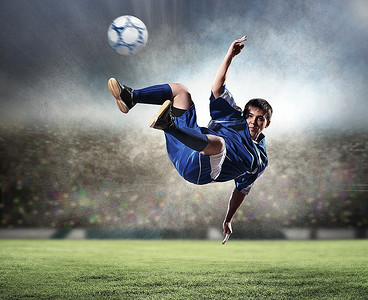 身着蓝色衬衫的足球运动员在体育场高空击球