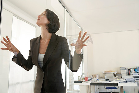 女商人站在办公室里，双手和脸靠在玻璃上。