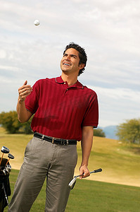高尔夫球手拿着推杆在空中抛高尔夫球