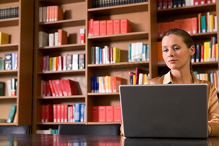 一名年轻女子在图书馆使用笔记本电脑