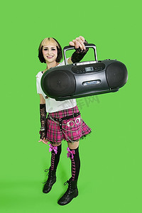 音箱店店招摄影照片_绿色背景上举着音箱的年轻女子肖像