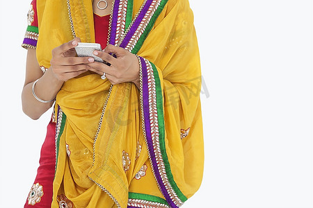 上半身穿着印度服装的妇女在灰色背景下使用手机
