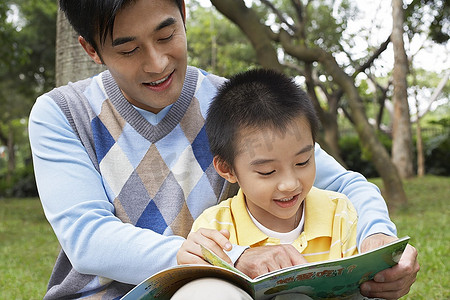 父子俩(7-9岁)在公园看书