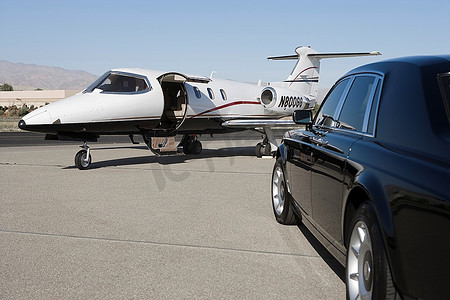 机场跑道上有豪华轿车和私人飞机。
