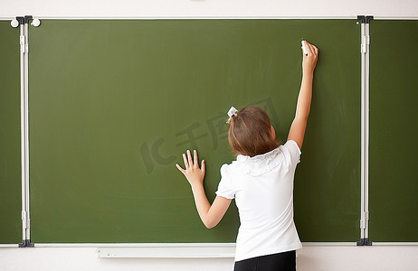 站在教室里一块绿色黑板旁的酷女
