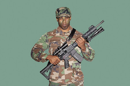 美国海军陆战队一名年轻的非裔美国士兵在绿色背景下手持M4突击步枪的肖像