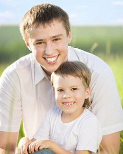获得摄影照片_愉快的父亲和儿子获得乐趣户外在春天绿色领域反对蓝天背景