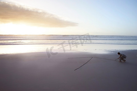 一箭穿心的箭摄影照片_一位青年商人在沙滩上的沙滩上射箭