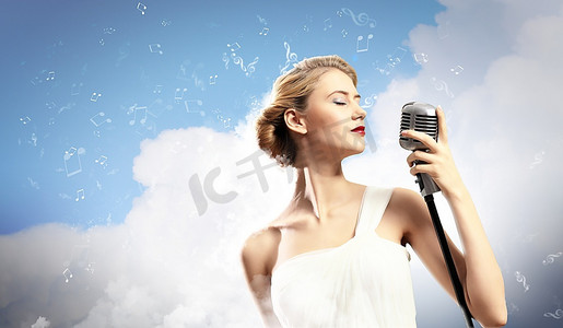 金发女歌手闭着眼睛拿着麦克风在云彩的背景下