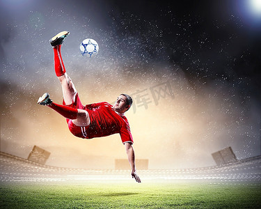 在红色衬衫的足球运动员在雨中在体育场击球