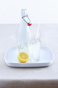小柠檬水摄影照片_陶瓷瓶、柠檬水玻璃杯和托盘上的柠檬