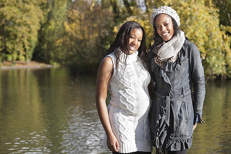 一位年轻的非洲裔美国妇女和她的朋友边喝咖啡或茶边聊天美女女孩怀孕