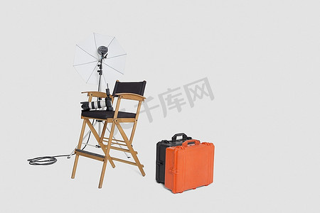 导演和锐利；演播室里有S椅子和带行李箱的反光伞