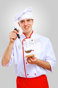 鼠年国潮背景摄影照片_穿着红色围裙的年轻男厨师在灰色背景下