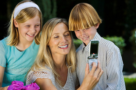 一名中年妇女与两个孩子用手机合影