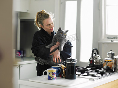 站在厨房里抱着猫的女人