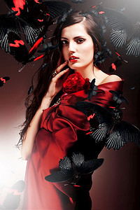 性感的女人在红色织物与红玫瑰和蝴蝶