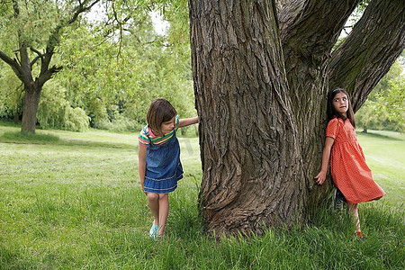 空空的树干摄影照片_两个女孩在玩捉迷藏
