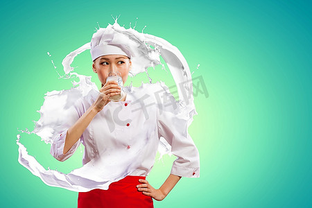 飞溅水花摄影照片_亚洲女厨师在喝牛奶的颜色背景下穿着红色围裙防止牛奶飞溅