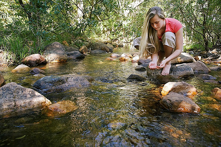 一名年轻女子在小溪里测试水