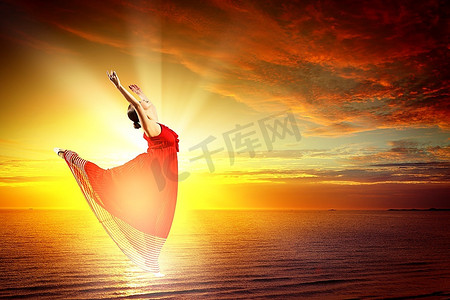 芭蕾摄影照片_在落日背景下，芭蕾舞女演员在水面上翱翔的形象