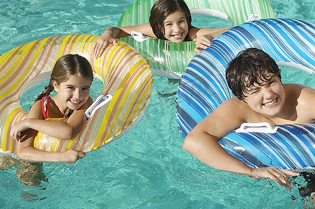 游泳池里的三个孩子坐在充气木筏上，肖像