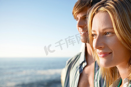年轻女子靠近海边背景中的年轻男子