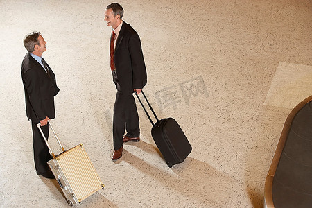 两个商人站在行李传送带在机场行李箱