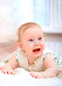 女性生气摄影照片_在浅色背景下哭泣的婴儿