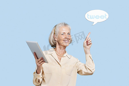 高级英语摄影照片_高级妇女的象象有指向tweet泡沫的片剂PC反对蓝色背景