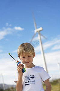 tshirt摄影照片_男孩（7-9）举行玩具走在风力发电场，肖像