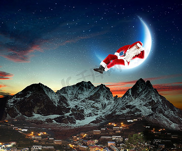 庆典动图摄影照片_圣诞老人坐在月球上的照片，下面是城市和山脉